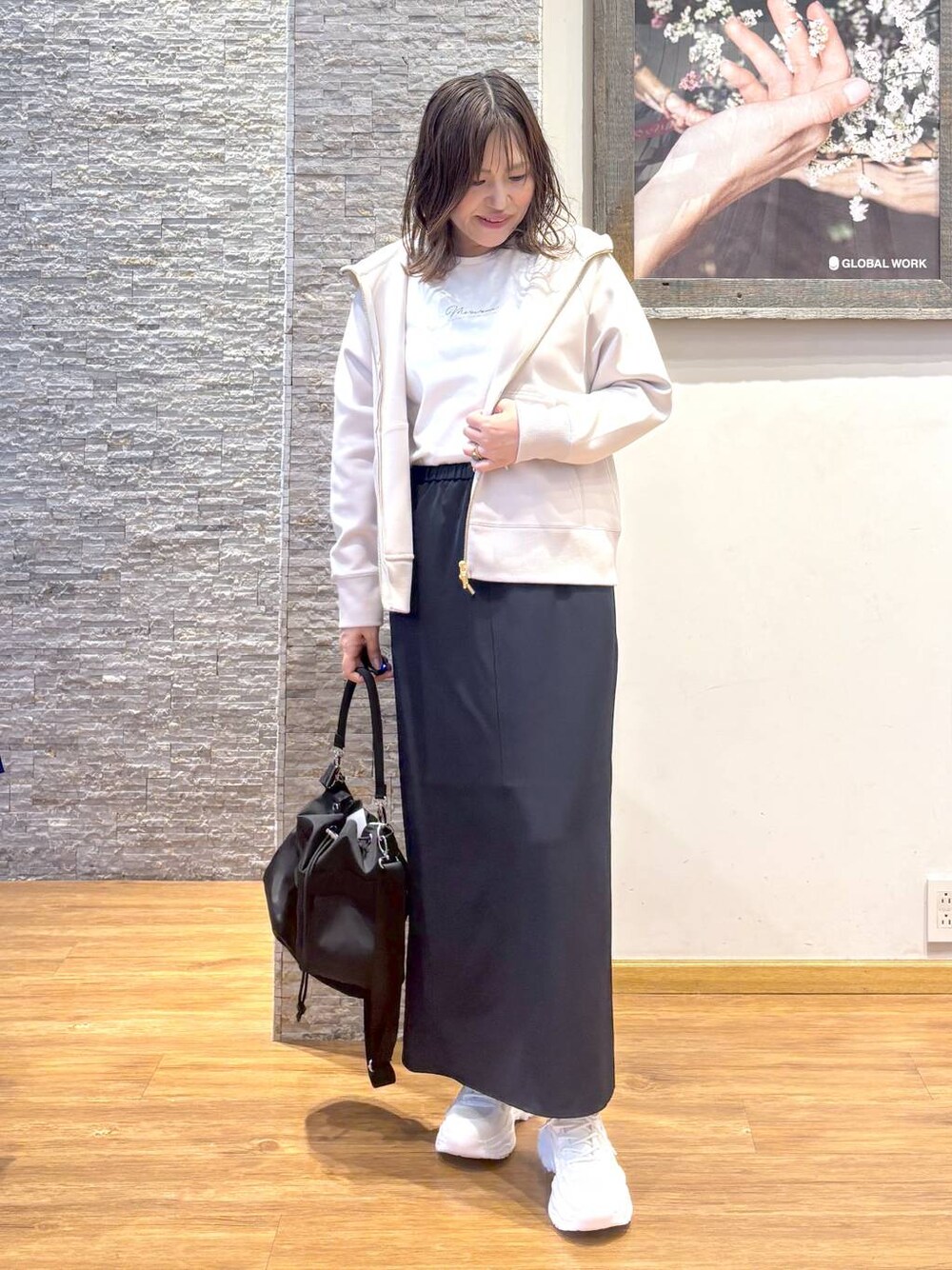 ホワイト系のショルダーバッグ、ブラック系のスカート、ホワイト系のスニーカーを着用したレディースの秋コーディネートの1枚目の写真
