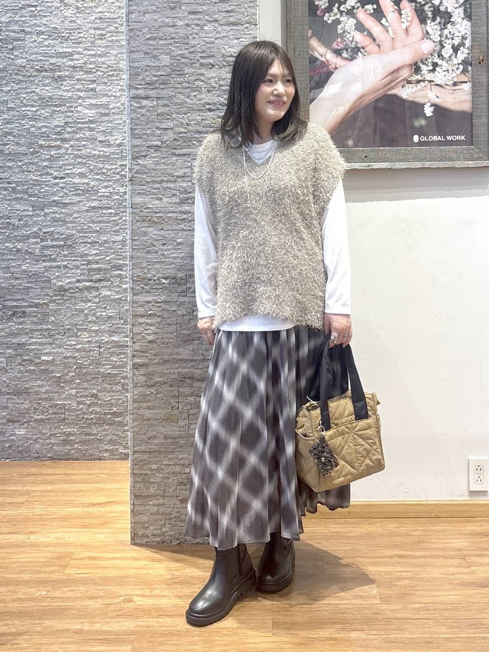 ブラウン系のトートバッグ、ブラウン系のスカート、ブラウン系のベストを着用したレディースの秋コーディネートの1枚目の写真