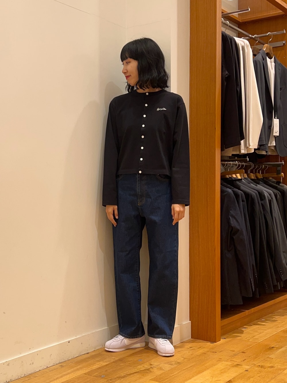 ブラック系のカーディガン/ボレロ、グレー系のスニーカー、ブルー系のデニムパンツを着用したレディースの秋コーディネートの1枚目の写真