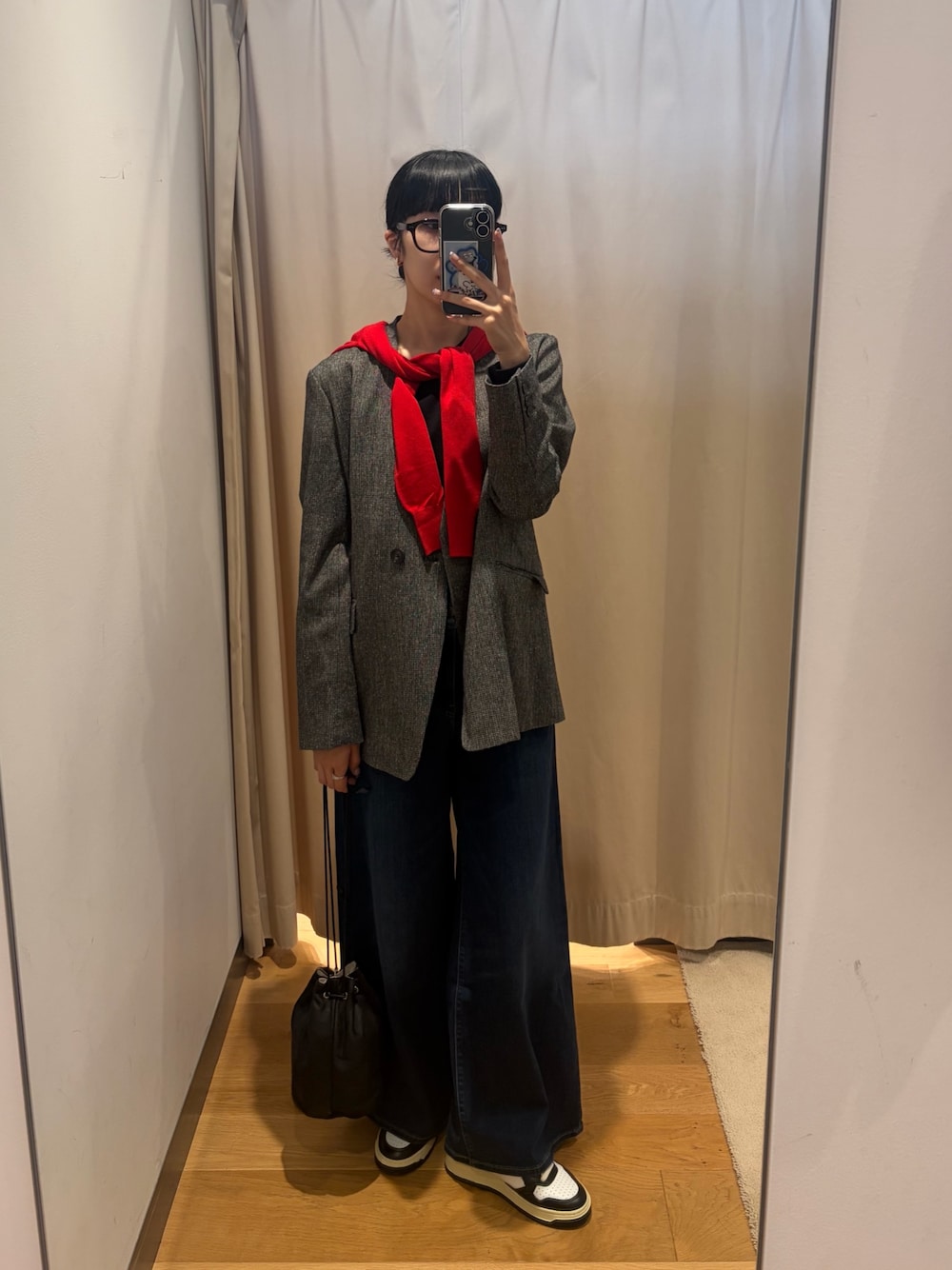 レッド系のカーディガン/ボレロ、ブルー系のデニムパンツ、ブラック系のショルダーバッグを着用したレディースの秋コーディネートの1枚目の写真