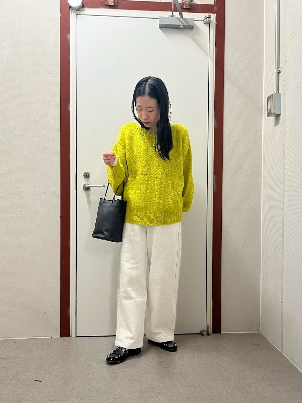 イエロー系のニット/セーター、ベージュ系のその他パンツ、ブラック系のローファーを着用したレディースの秋コーディネートの1枚目の写真