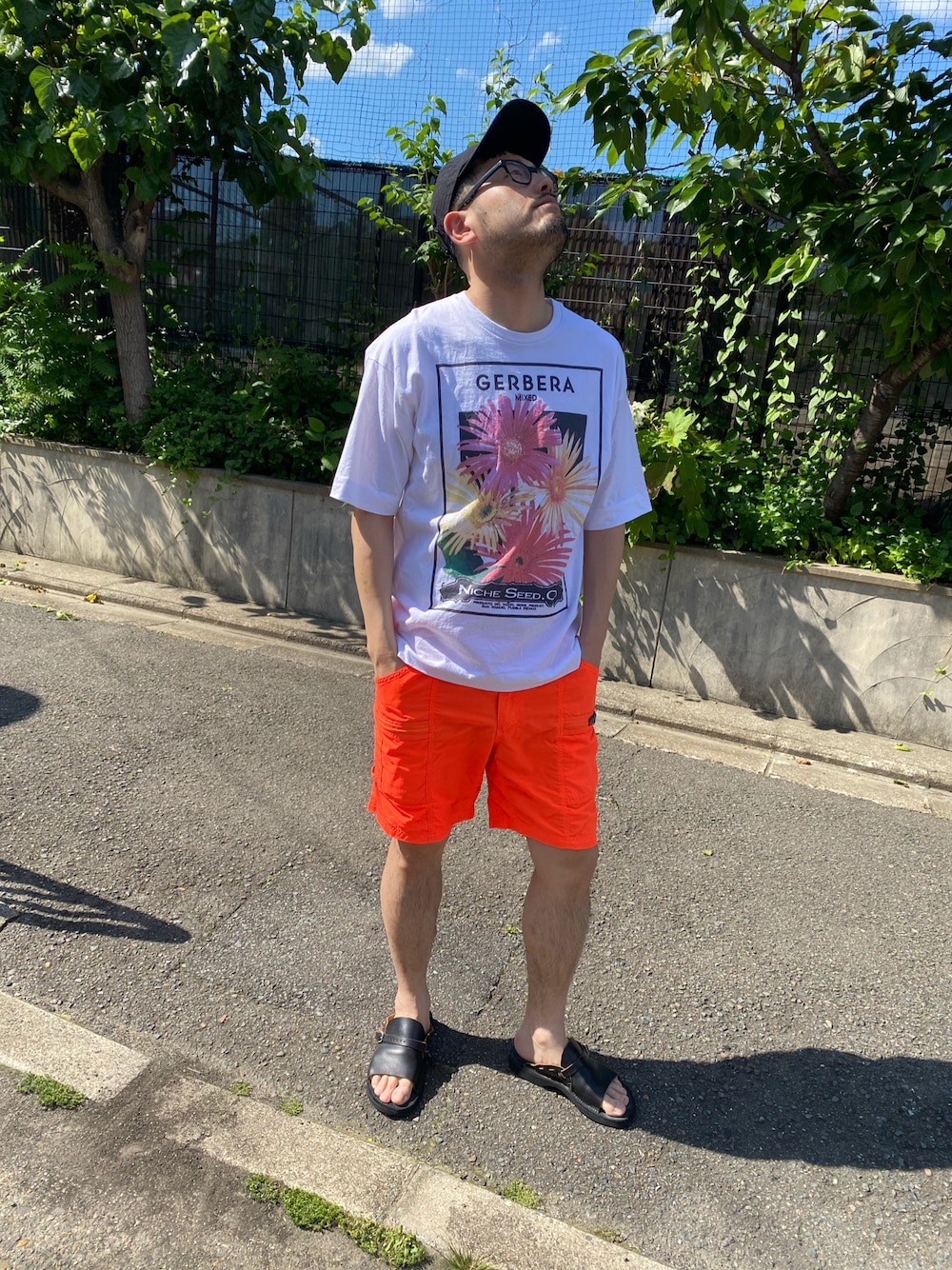 ホワイト系のTシャツ/カットソー、オレンジ系のその他パンツ、ブラック系のサンダルを着用したメンズの秋コーディネートの1枚目の写真