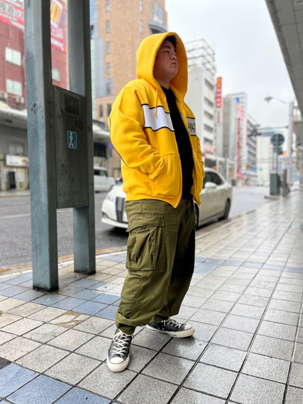 イエロー系のパーカー、ブラック系のTシャツ/カットソー、グリーン系のカーゴパンツを着用したメンズの秋コーディネートの1枚目の写真