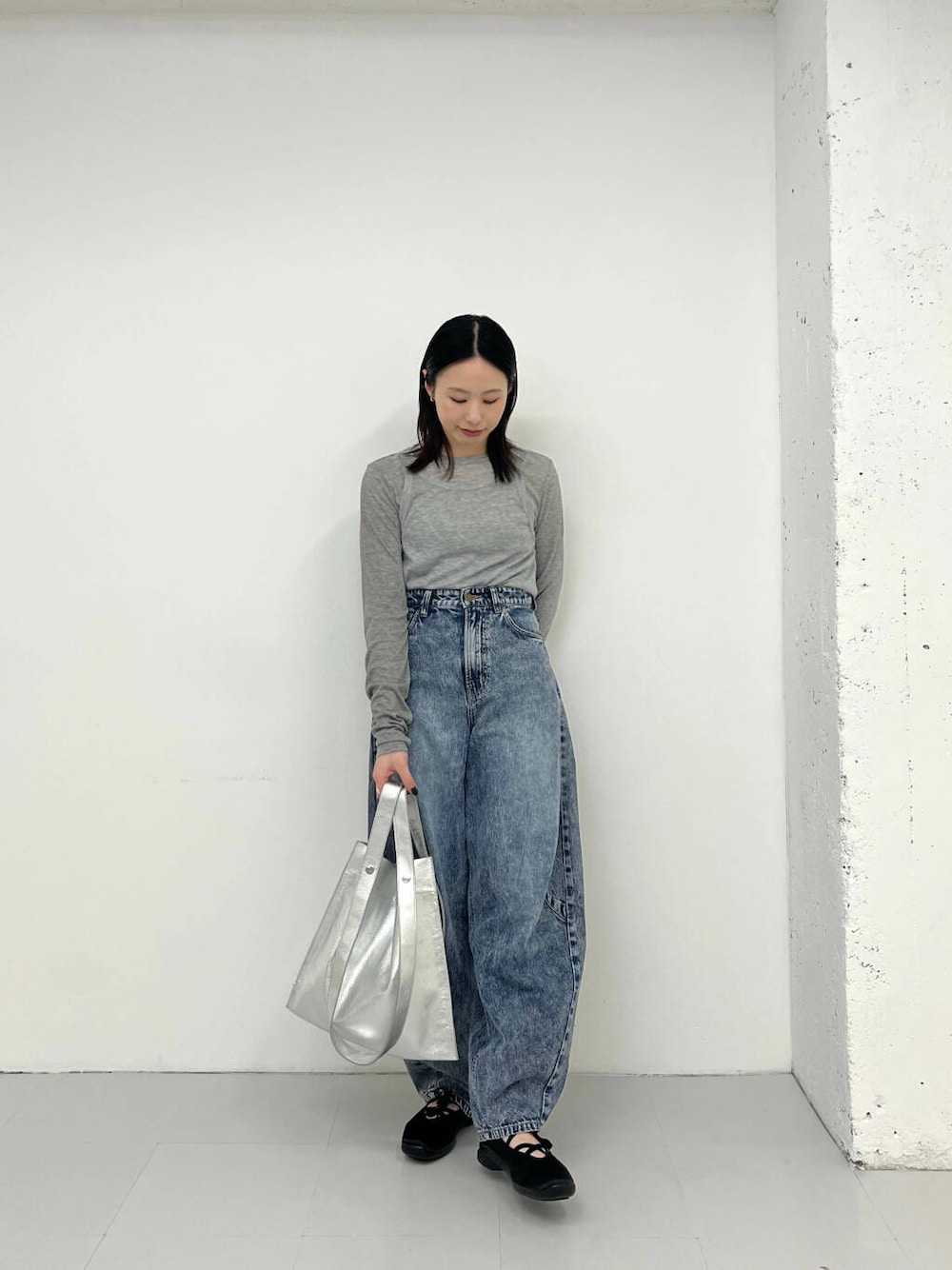 ブルー系のデニムパンツ、ブラック系のスニーカー、シルバー系のトートバッグを着用したレディースの春コーディネートの1枚目の写真