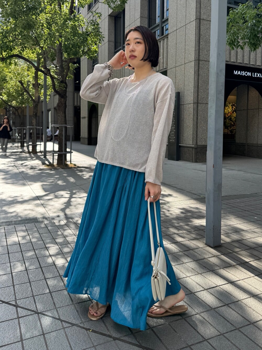 ブルー系のワンピース、ベージュ系のニット/セーター、ホワイト系のショルダーバッグを着用したレディースの夏コーディネートの1枚目の写真