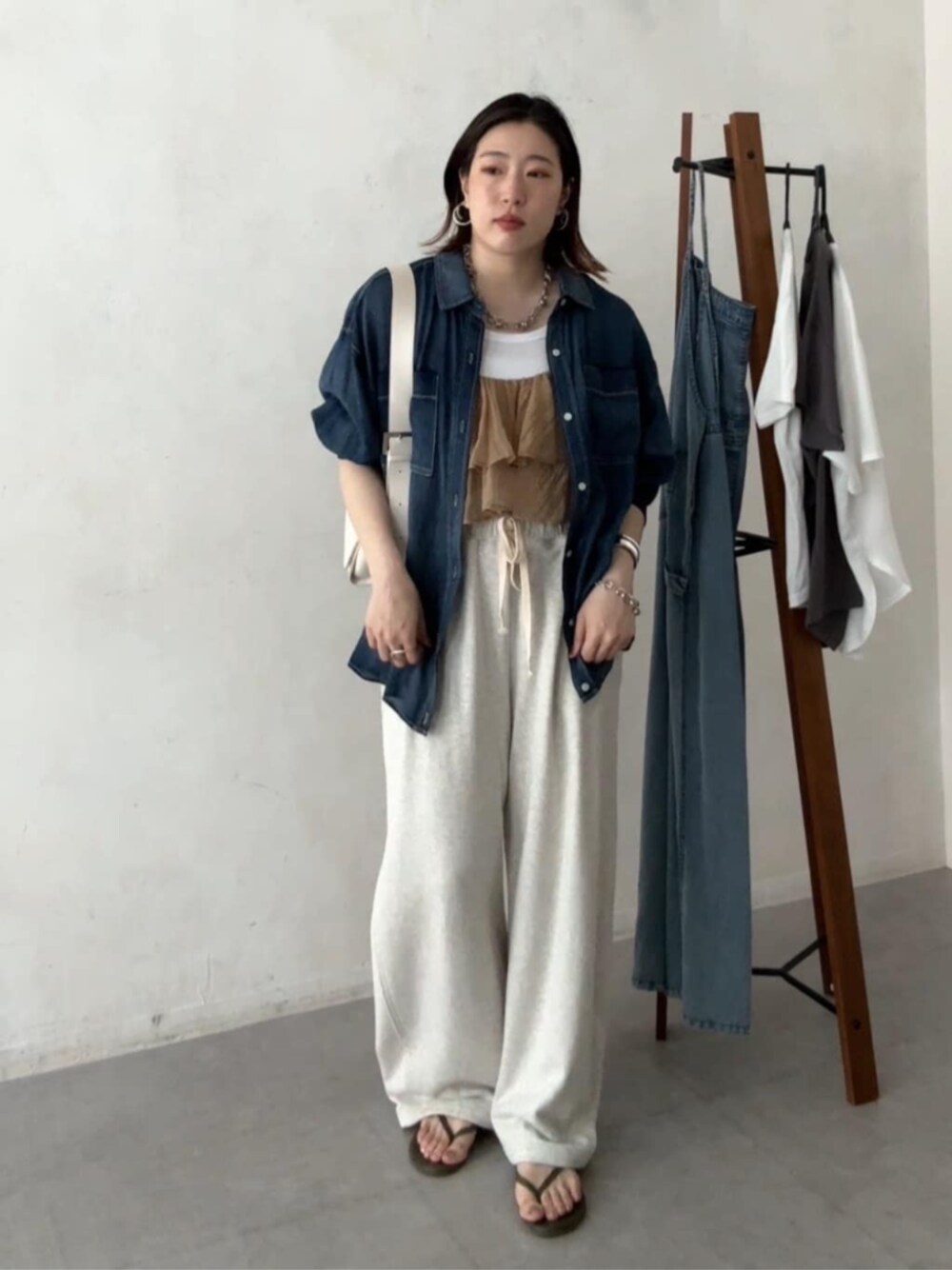 ホワイト系のショルダーバッグ、ベージュ系のその他パンツ、ブルー系のシャツ/ブラウスを着用したレディースの春コーディネートの1枚目の写真