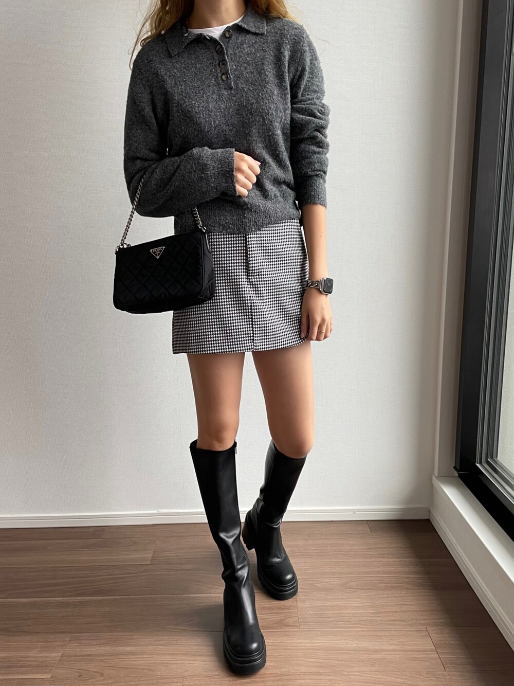 ブラック系のスカート、ブラック系のブーツ、ブラック系のハンドバッグを着用したレディースの秋コーディネートの1枚目の写真