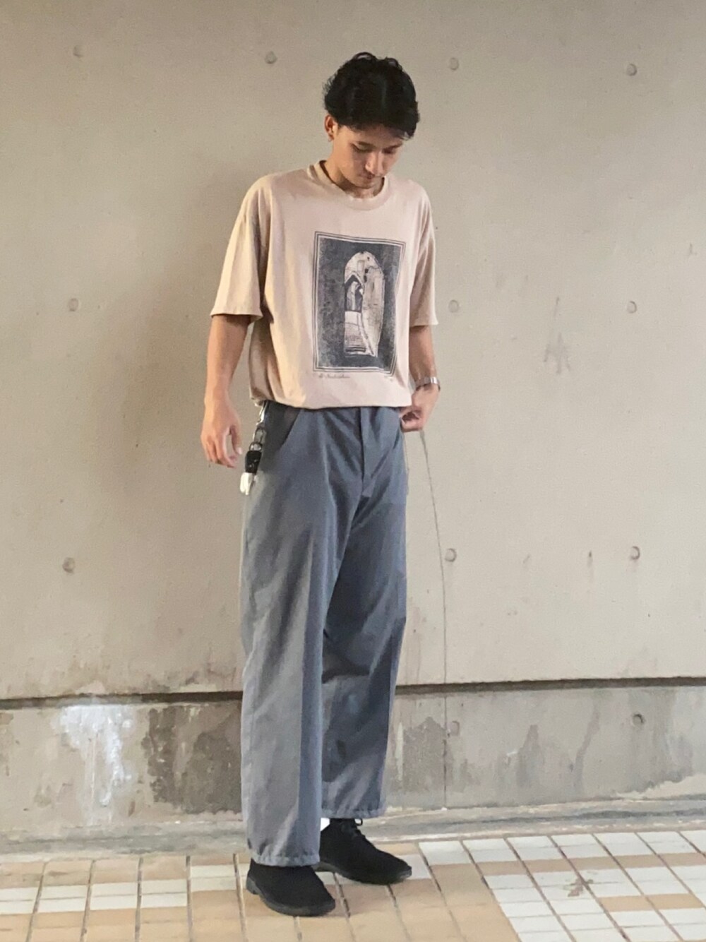 ブラック系のシューズ、グレー系のスラックス、ベージュ系のTシャツ/カットソーを着用したメンズの春コーディネートの1枚目の写真