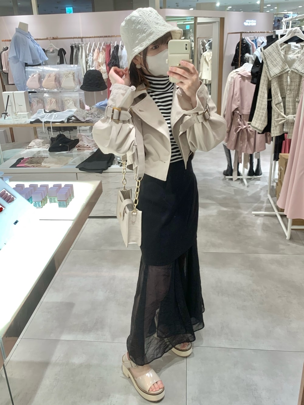 ベージュ系のトレンチコート、ホワイト系のショルダーバッグ、ベージュ系のサンダルを着用したレディースの春コーディネートの1枚目の写真