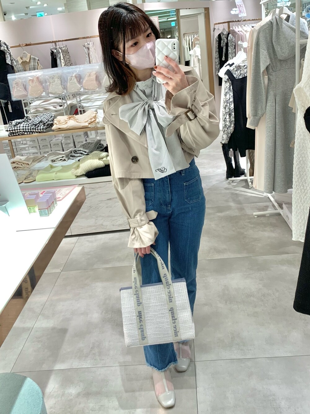 ベージュ系のトレンチコート、グレー系のブーツ、ブルー系のデニムパンツを着用したレディースの春コーディネートの1枚目の写真