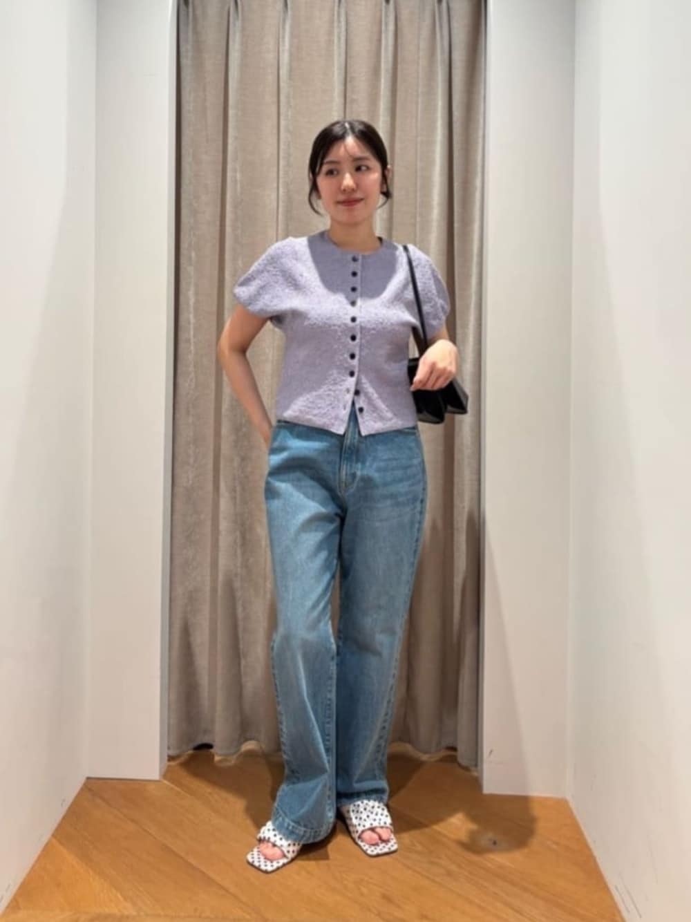 ブルー系のデニムパンツ、ブラック系のショルダーバッグ、ホワイト系のサンダルを着用したレディースの春コーディネートの1枚目の写真