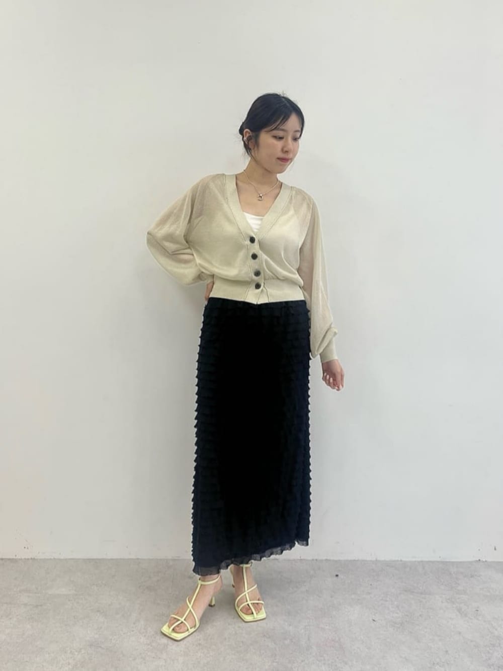 グレー系のカーディガン/ボレロ、ブラック系のスカート、グリーン系のサンダルを着用したレディースの夏コーディネートの1枚目の写真