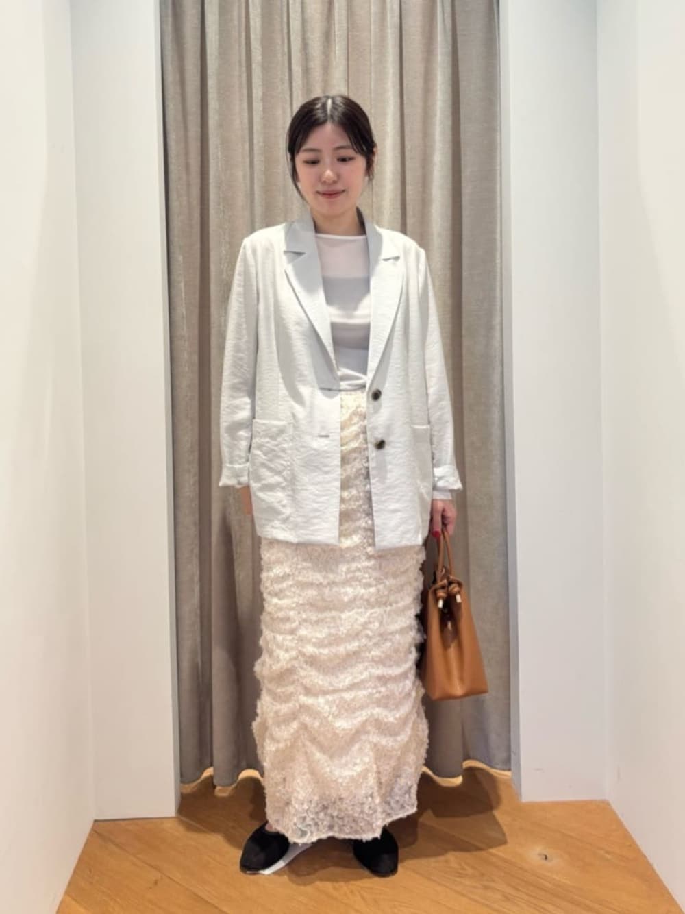 グリーン系のテーラードジャケット、ホワイト系のTシャツ/カットソー、ホワイト系のスカートを着用したレディースの冬コーディネートの1枚目の写真