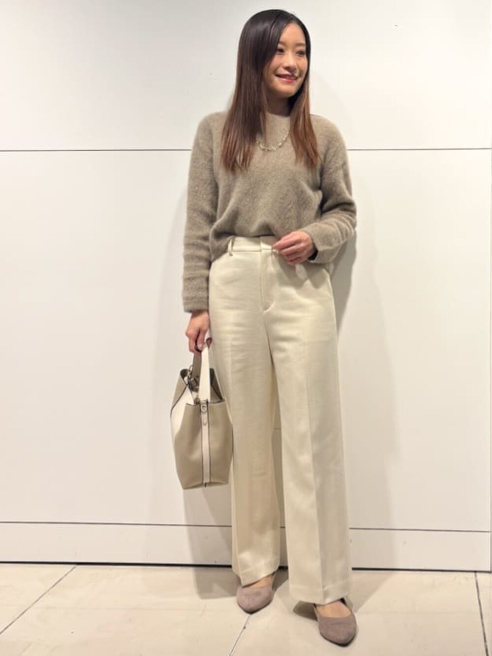 ベージュ系のニット/セーター、ホワイト系のその他パンツ、ベージュ系のショルダーバッグを着用したレディースの冬コーディネートの1枚目の写真