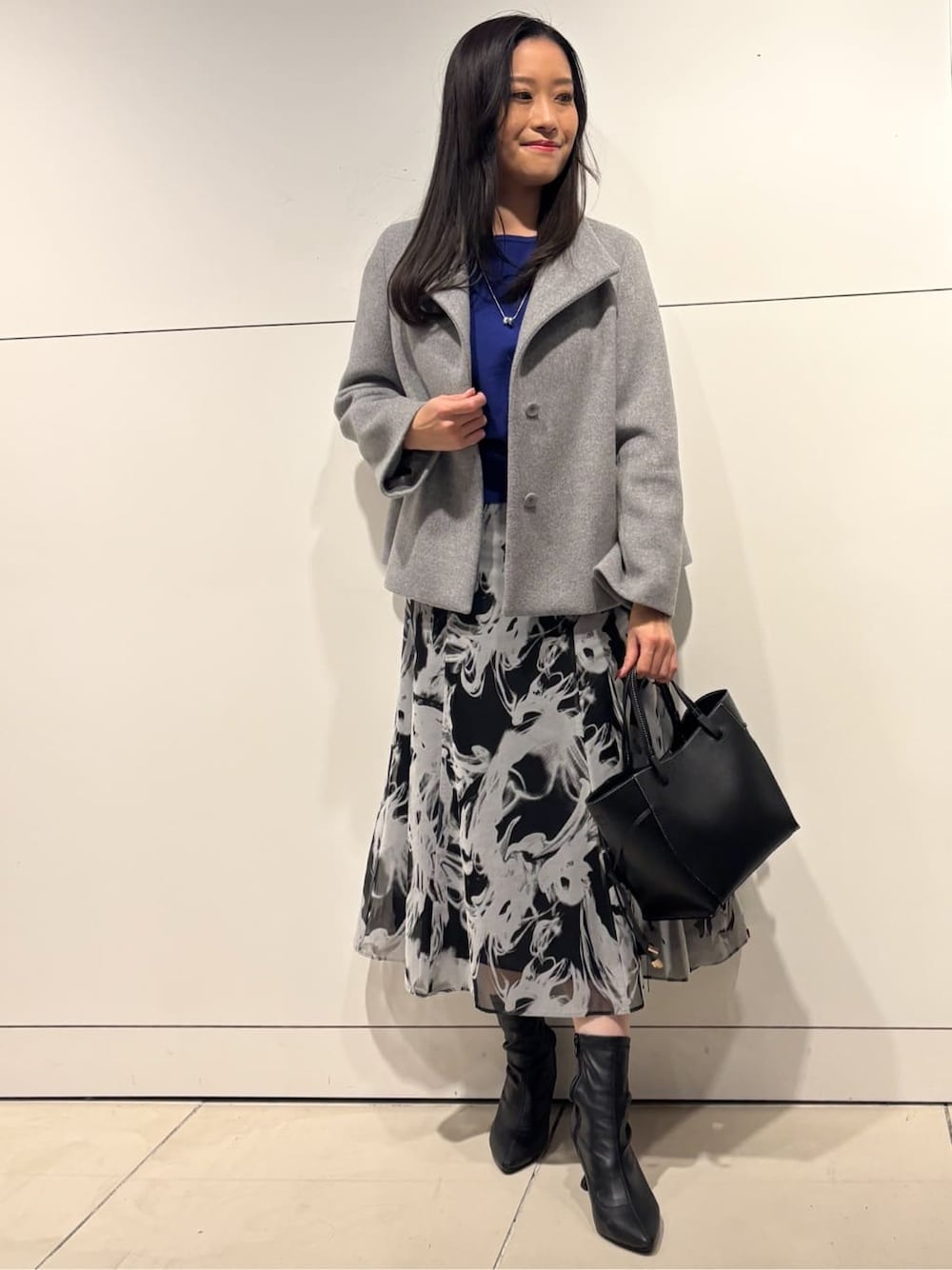 グレー系のスカート、グレー系のその他アウター、シルバー系のネックレスを着用したレディースの冬コーディネートの1枚目の写真