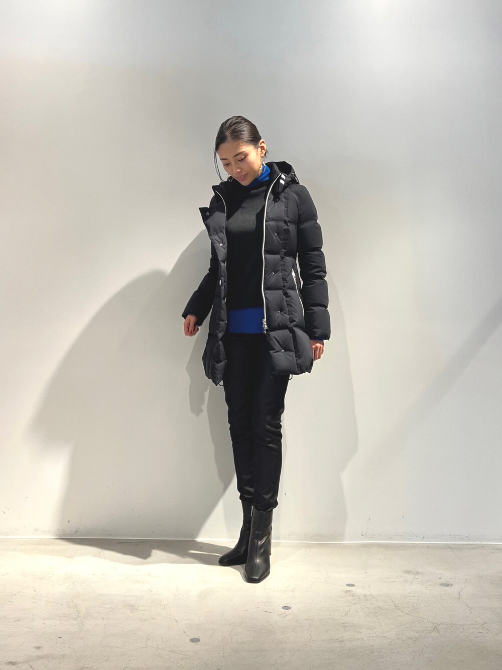 ブラック系のダウンジャケット/コート、グレー系のニット/セーター、ブラック系のブーツを着用したレディースの冬コーディネートの1枚目の写真