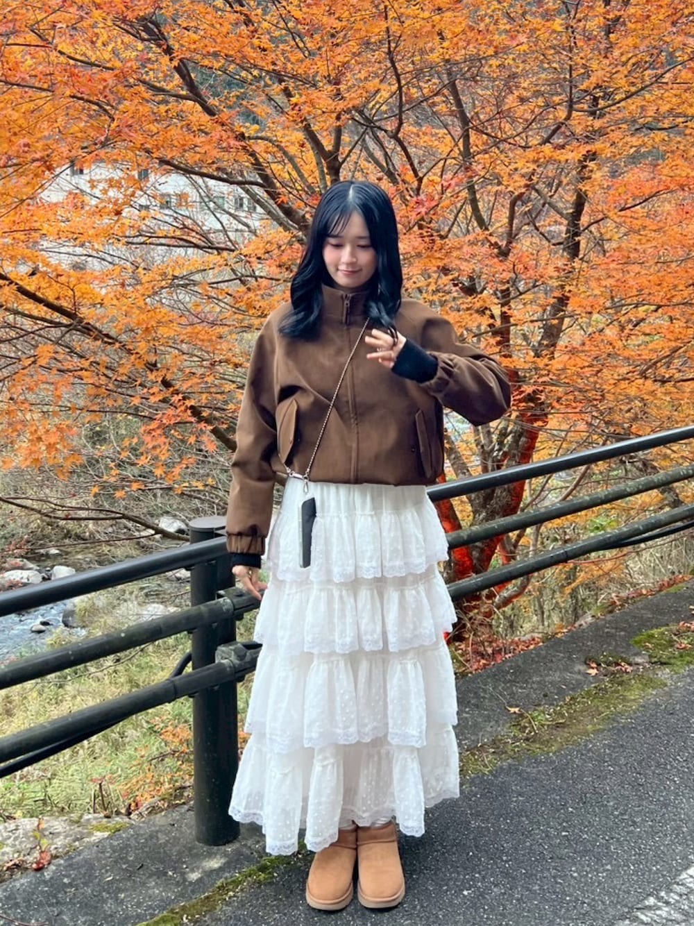 ホワイト系のスカート、ブラウン系のブーティ、ブラウン系のブルゾンを着用したレディースの秋コーディネートの1枚目の写真