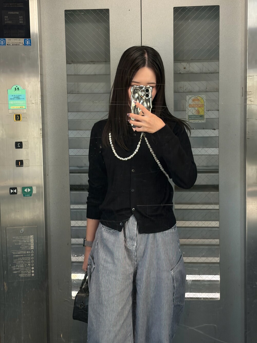 ブラック系のカーディガン/ボレロ、ブルー系のデニムパンツ、ブラック系のショルダーバッグを着用したレディースの秋コーディネートの1枚目の写真