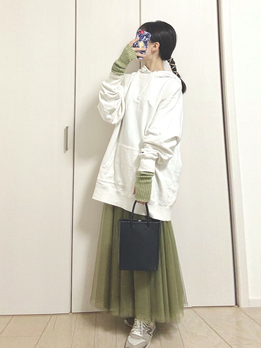 ブラック系のショルダーバッグ、ホワイト系のパーカー、グリーン系のスカートを着用したレディースの秋コーディネートの1枚目の写真