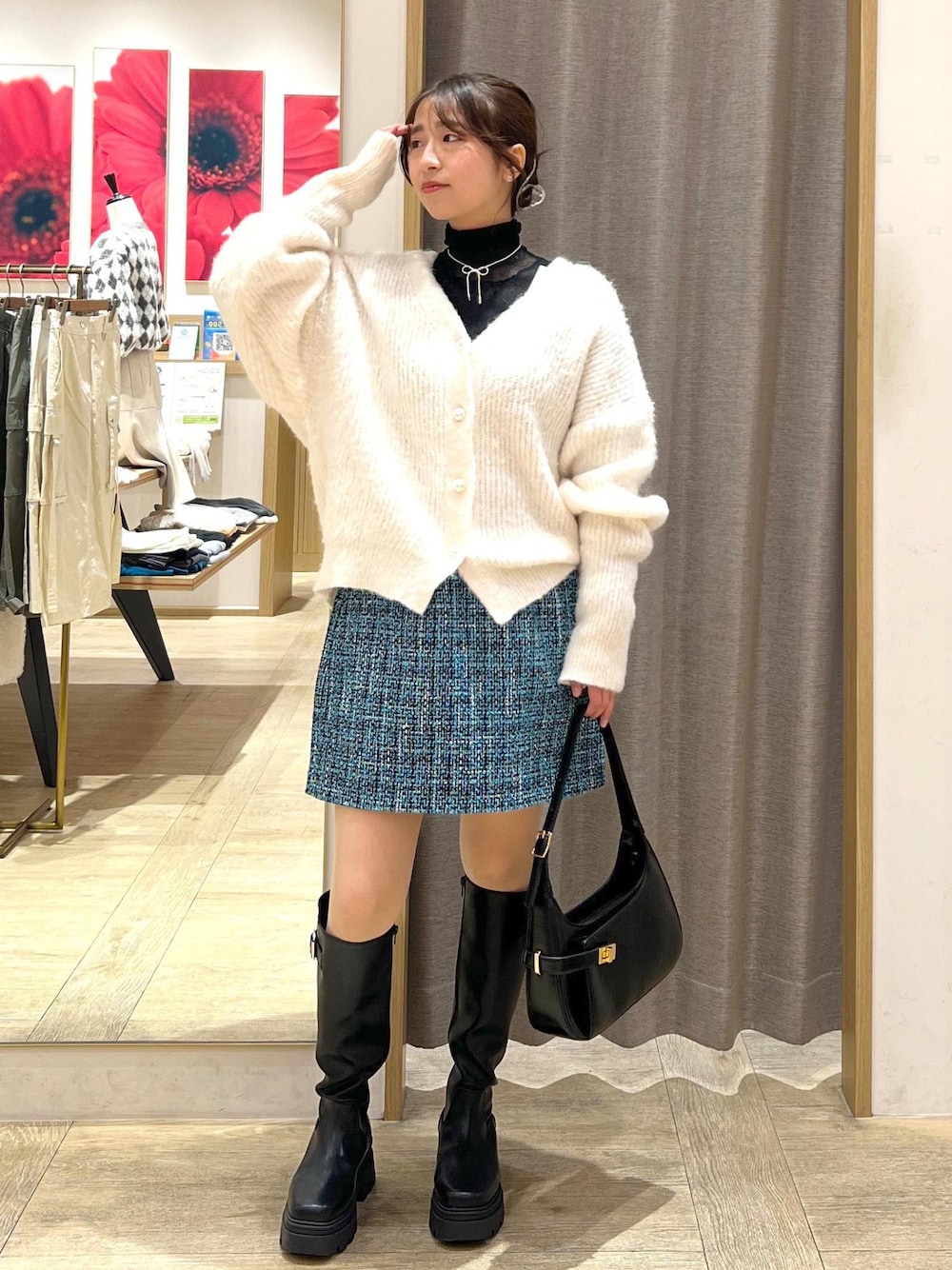 ブラック系のブーツ、ブルー系のスカート、ホワイト系のカーディガン/ボレロを着用したレディースの冬コーディネートの1枚目の写真