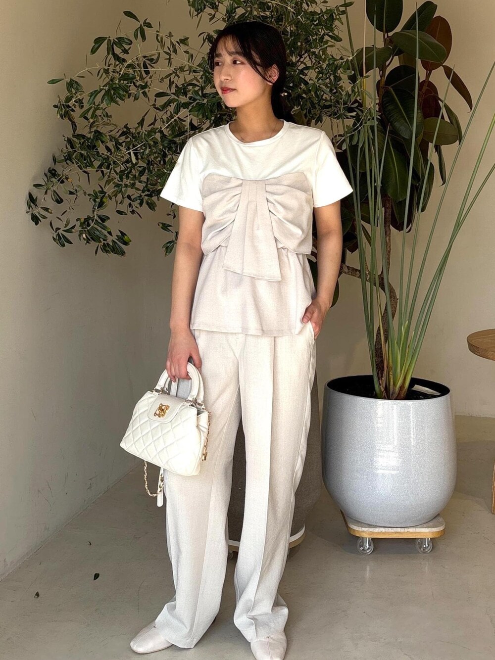 ホワイト系のパンプス、ホワイト系のTシャツ/カットソー、ホワイト系のスラックスを着用したレディースの春コーディネートの1枚目の写真