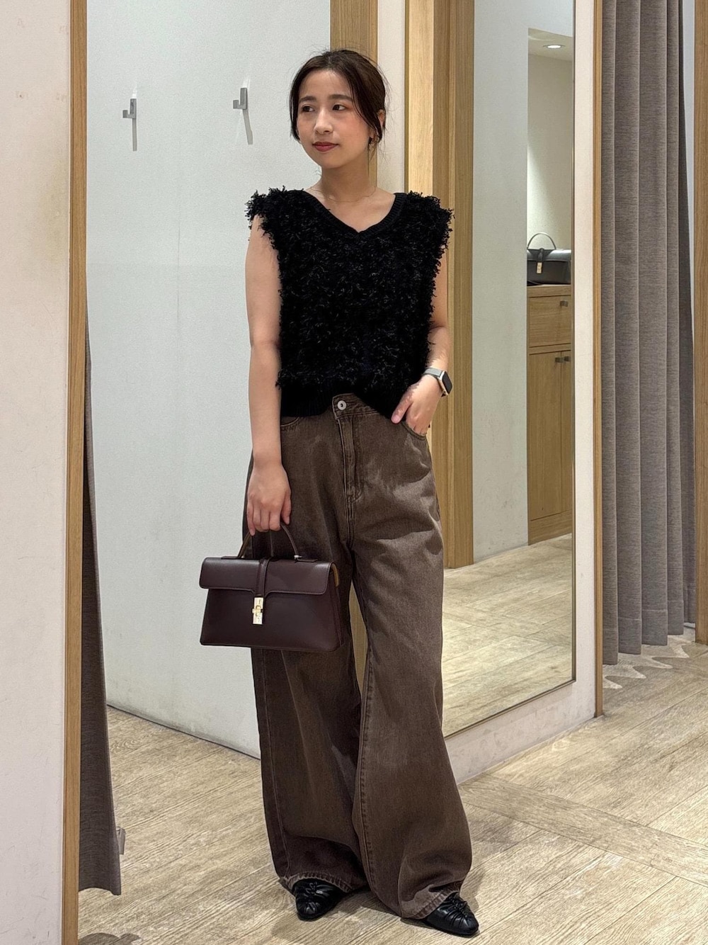 ブラウン系のショルダーバッグ、ブラック系のパンプス、ブラック系のベストを着用したレディースの秋コーディネートの1枚目の写真