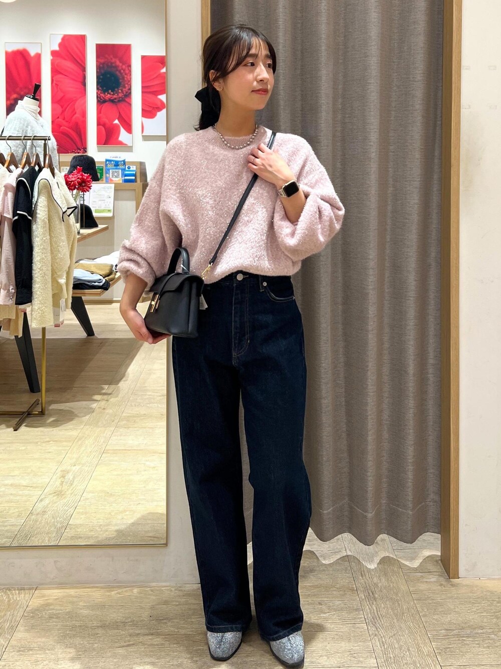 ブラック系のショルダーバッグ、シルバー系のブーツ、ブルー系のデニムパンツを着用したレディースの冬コーディネートの1枚目の写真