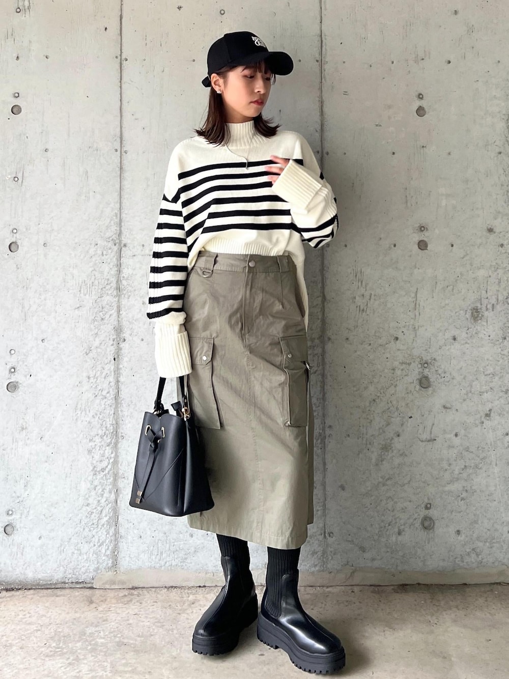 ブラック系のブーツ、グリーン系のスカート、ホワイト系のニット/セーターを着用したレディースの秋コーディネートの1枚目の写真