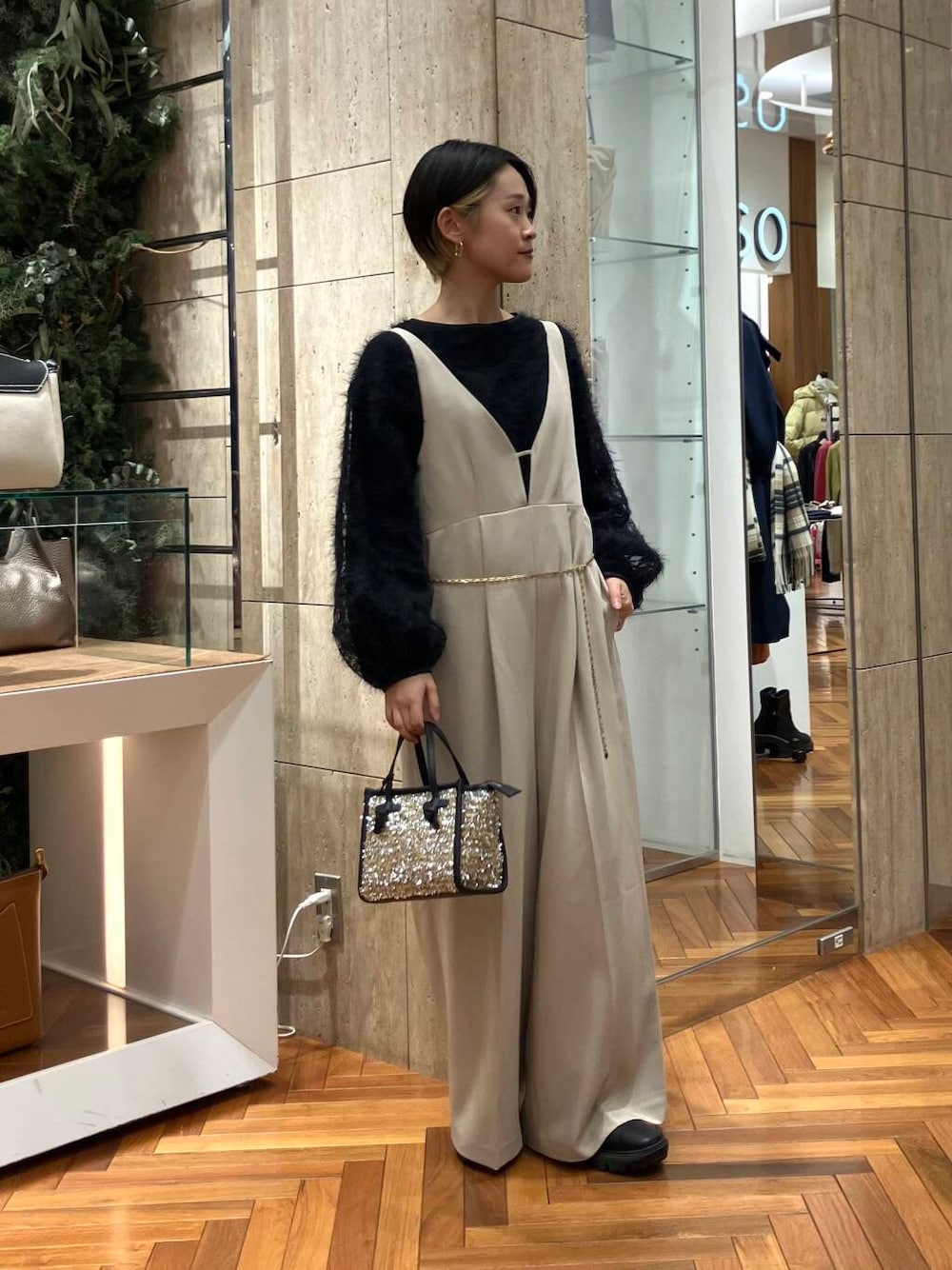 イエロー系のハンドバッグ、ブラック系のシャツ/ブラウス、ベージュ系のサロペット/オーバーオールを着用したレディースの冬コーディネートの1枚目の写真