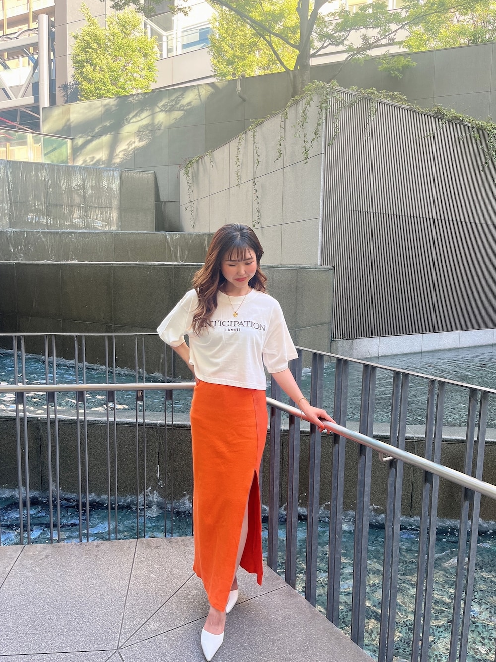 ホワイト系のTシャツ/カットソー、オレンジ系のスカート、ホワイト系のパンプスを着用したレディースの夏コーディネートの1枚目の写真