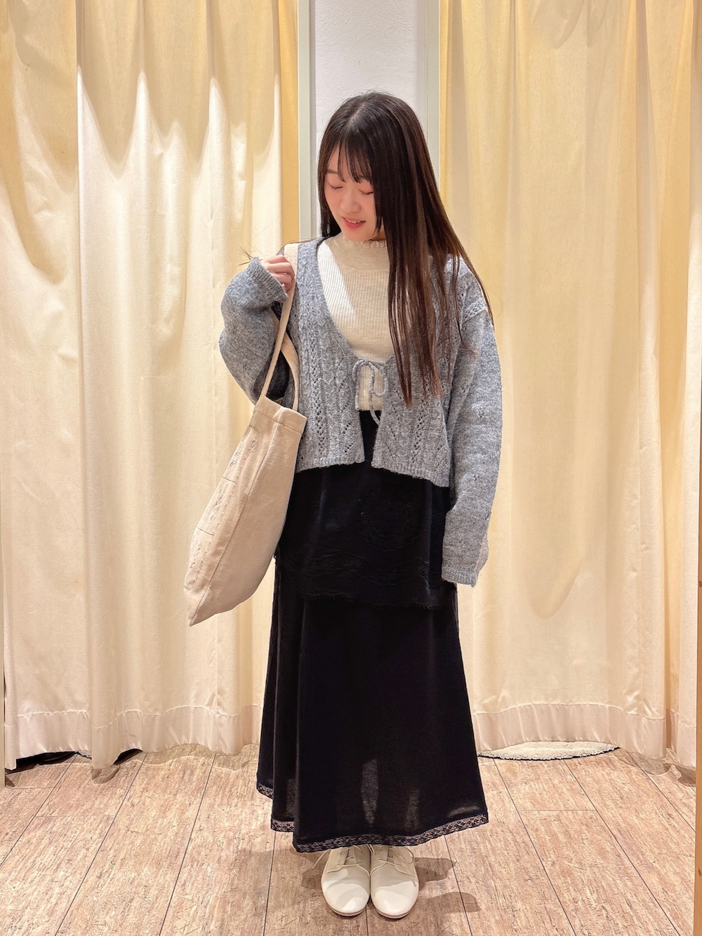ベージュ系のハンドバッグ、グレー系のカーディガン/ボレロ、ホワイト系のニット/セーターを着用したレディースの秋コーディネートの1枚目の写真