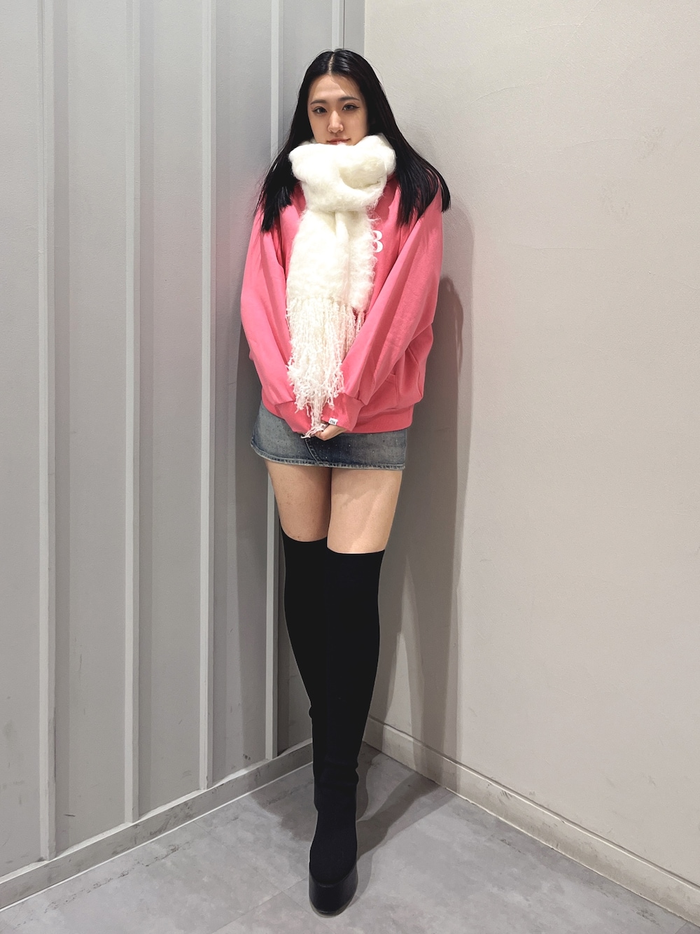 ブラック系のデニムスカート、ブラック系のブーツ、ピンク系のパーカーを着用したレディースの冬コーディネートの1枚目の写真