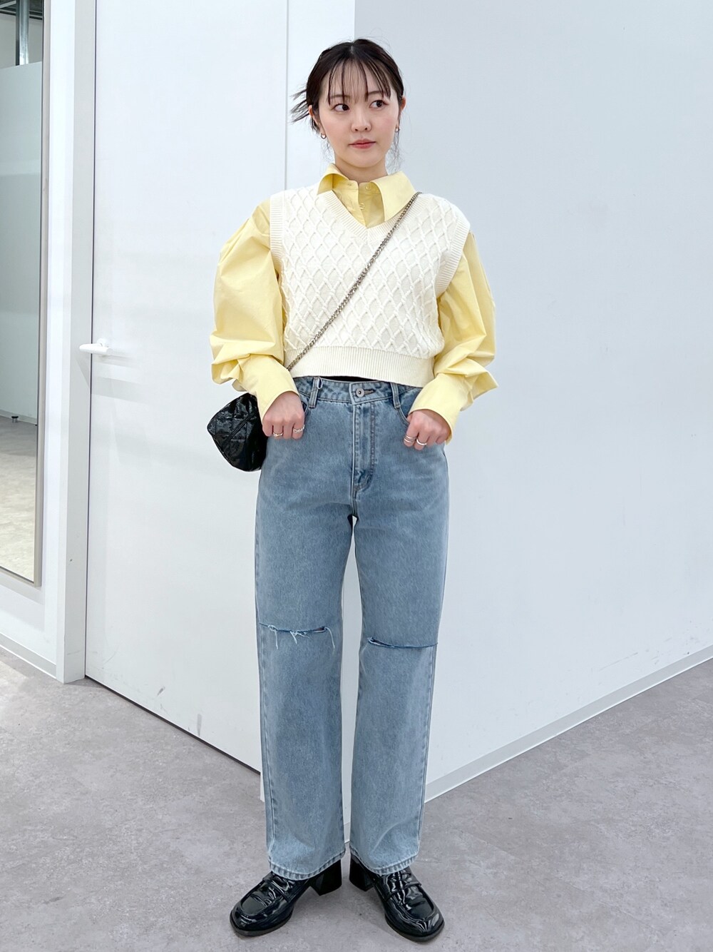 ホワイト系のベスト、イエロー系のシャツ/ブラウス、ブルー系のデニムパンツを着用したレディースの春コーディネートの1枚目の写真