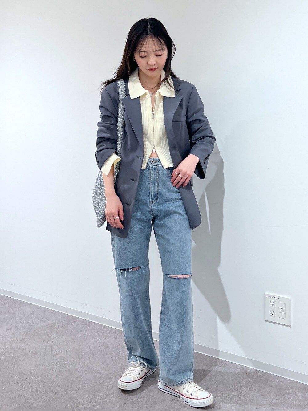 ブルー系のデニムパンツ、グレー系のテーラードジャケット、ホワイト系のニット/セーターを着用したレディースの春コーディネートの1枚目の写真