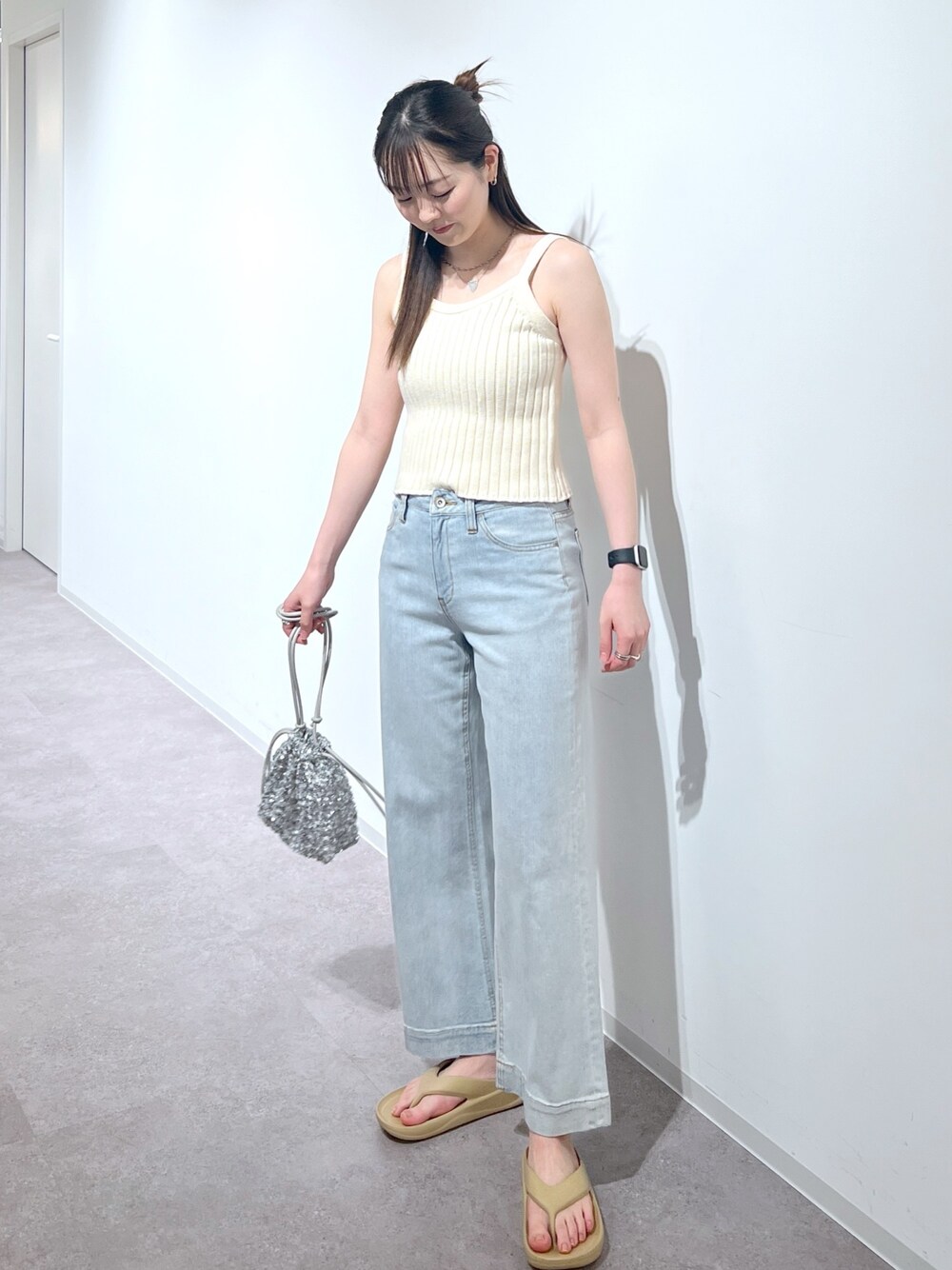 ホワイト系のタンクトップ、ブルー系のデニムパンツ、シルバー系のハンドバッグを着用したレディースの夏コーディネートの1枚目の写真