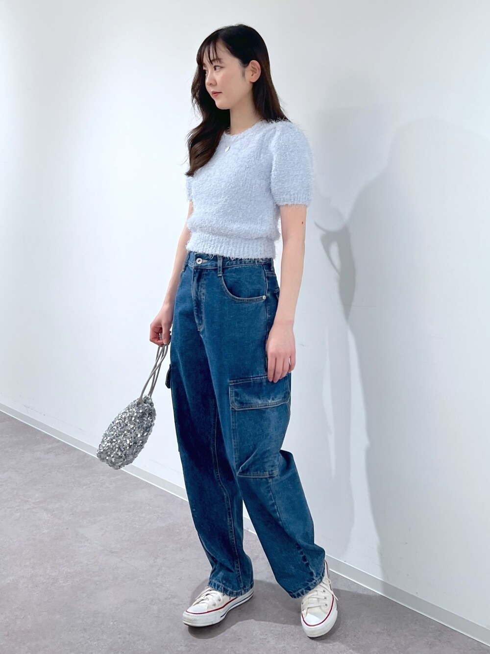ブルー系のニット/セーター、ブルー系のデニムパンツ、シルバー系のハンドバッグを着用したレディースの春コーディネートの1枚目の写真