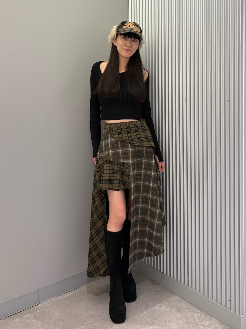 グリーン系のスカート、ブラック系のニット/セーター、ブラック系のブーツを着用したレディースの秋コーディネートの1枚目の写真