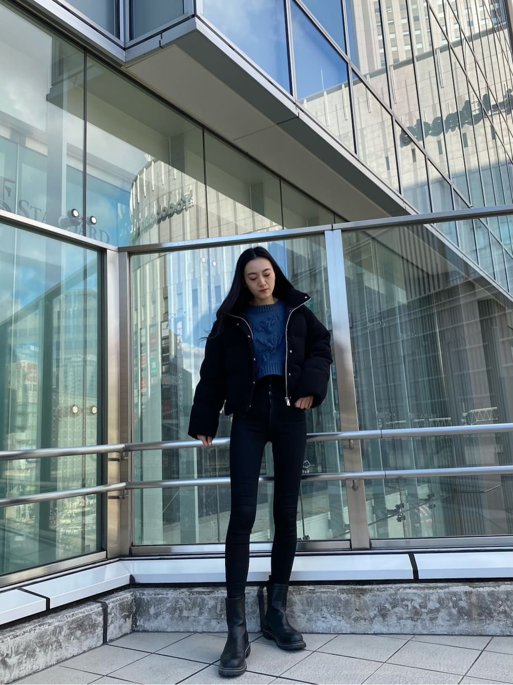 ブラック系のデニムパンツ、ブラック系のダウンジャケット/コート、ブルー系のニット/セーターを着用したレディースの冬コーディネートの1枚目の写真