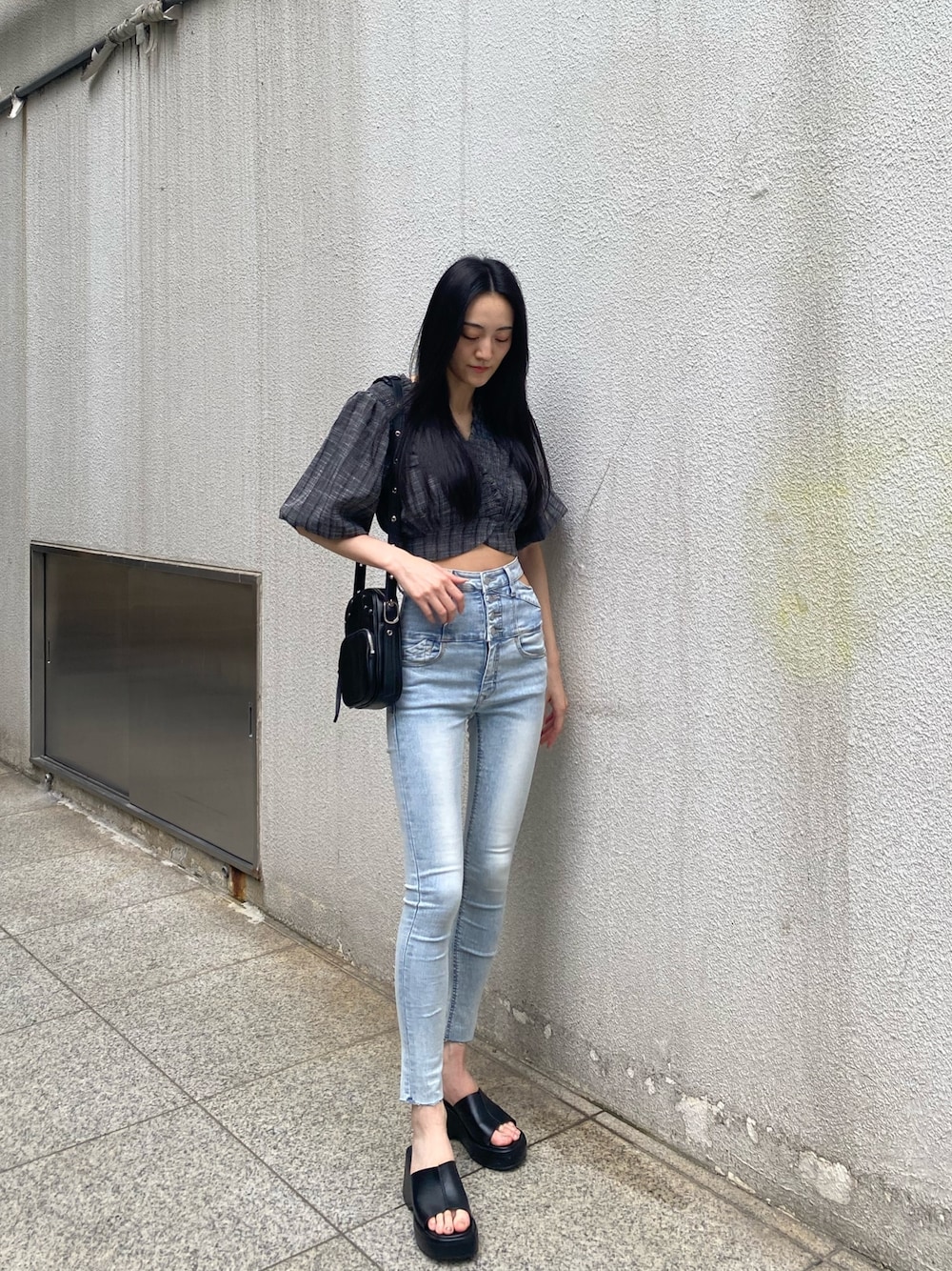 ブラック系のショルダーバッグ、ブラック系のTシャツ/カットソー、ブルー系のデニムパンツを着用したレディースの夏コーディネートの1枚目の写真