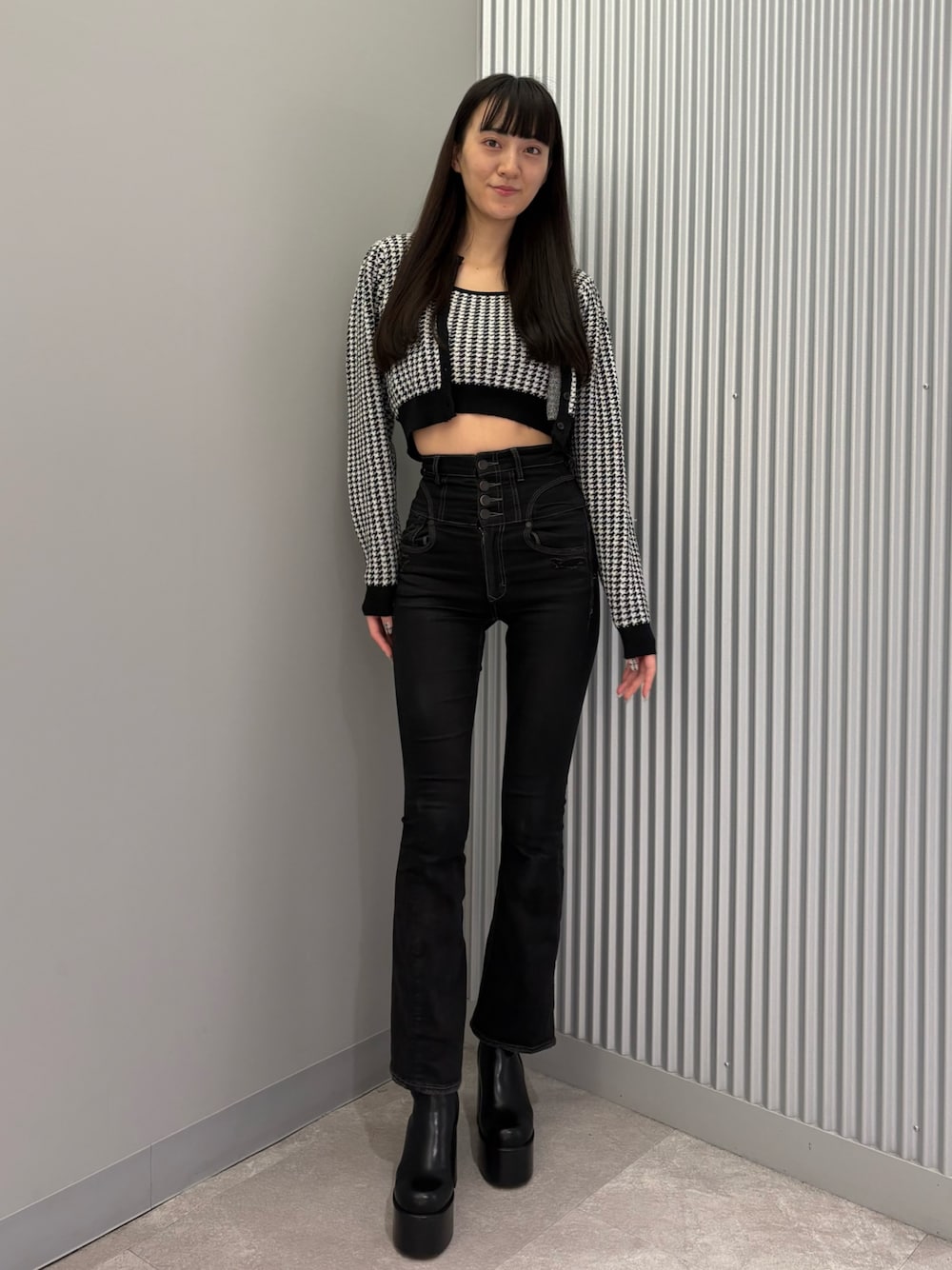 ブラック系のデニムパンツ、ブラック系のニット/セーター、ブラック系のブーツを着用したレディースの秋コーディネートの1枚目の写真