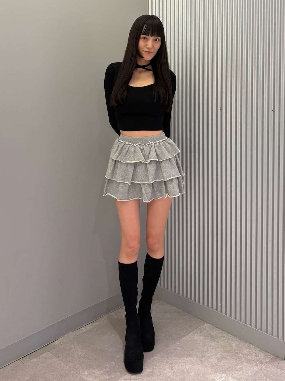グレー系のスカート、ブラック系のニット/セーター、ブラック系のブーツを着用したレディースの秋コーディネートの1枚目の写真