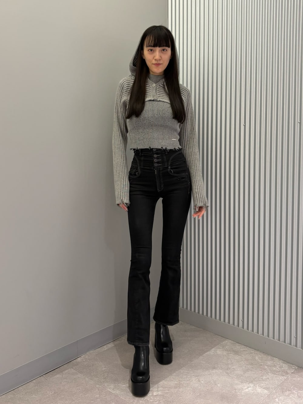 ブラック系のデニムパンツ、ブラック系のブーツ、グレー系のニット/セーターを着用したレディースの秋コーディネートの1枚目の写真