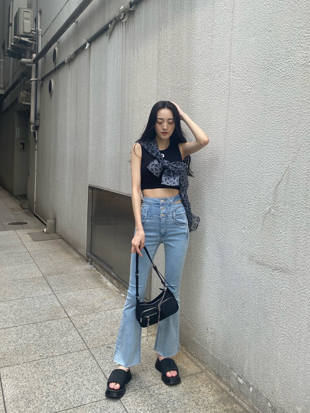 ブルー系のデニムパンツ、ブラック系のハンドバッグ、ブラック系のサンダルを着用したレディースの夏コーディネートの1枚目の写真