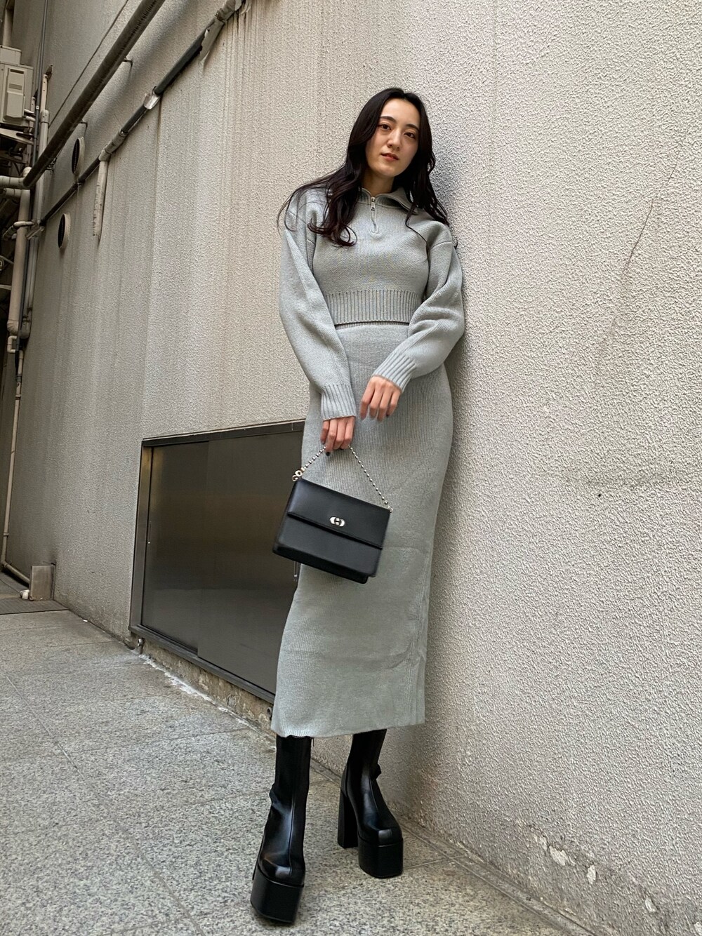 ブラック系のハンドバッグ、グレー系のスカート、グレー系のニット/セーターを着用したレディースの冬コーディネートの1枚目の写真