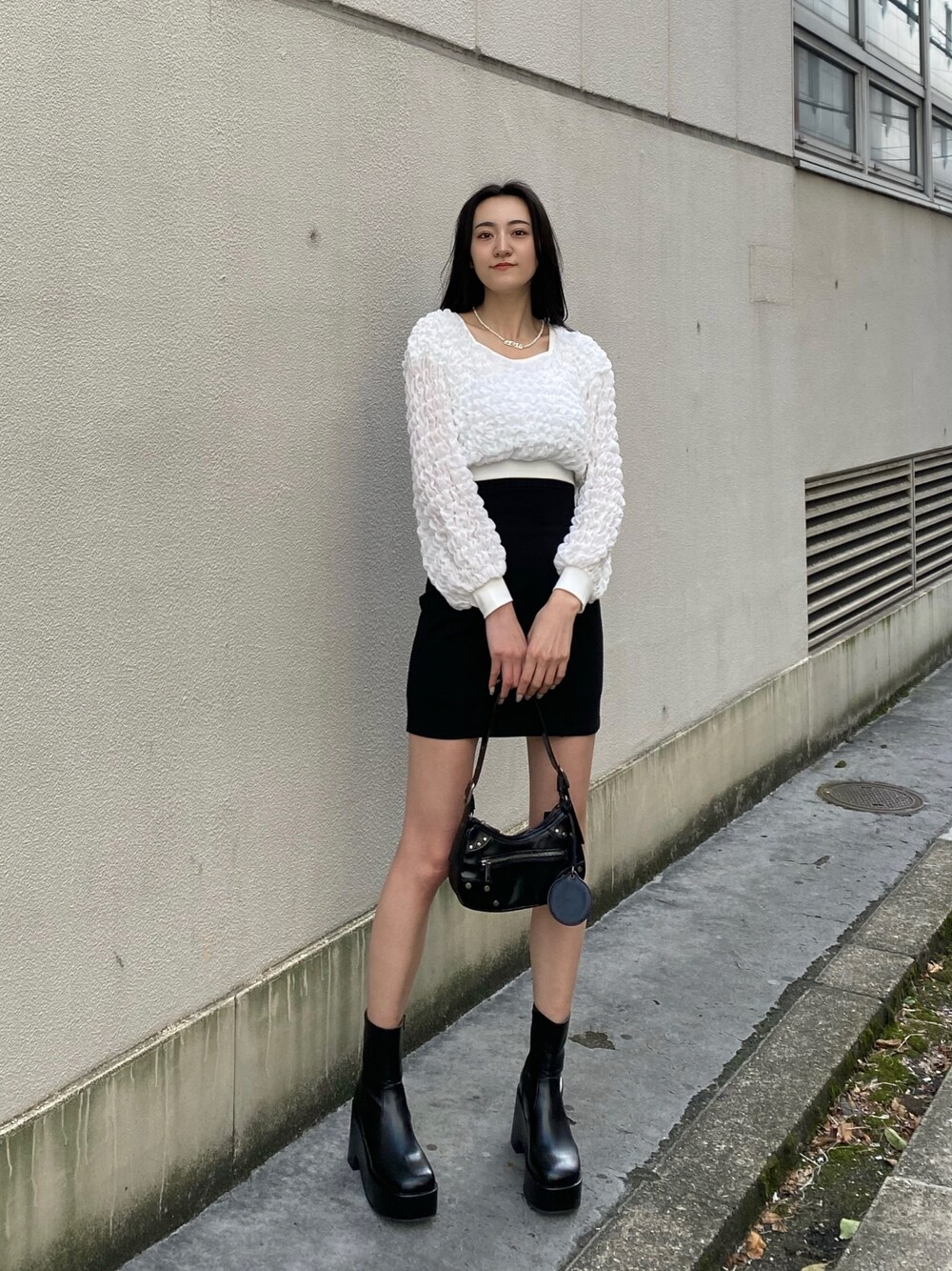 ホワイト系のTシャツ/カットソー、ブラック系のスカート、ブラック系のハンドバッグを着用したレディースの春コーディネートの1枚目の写真