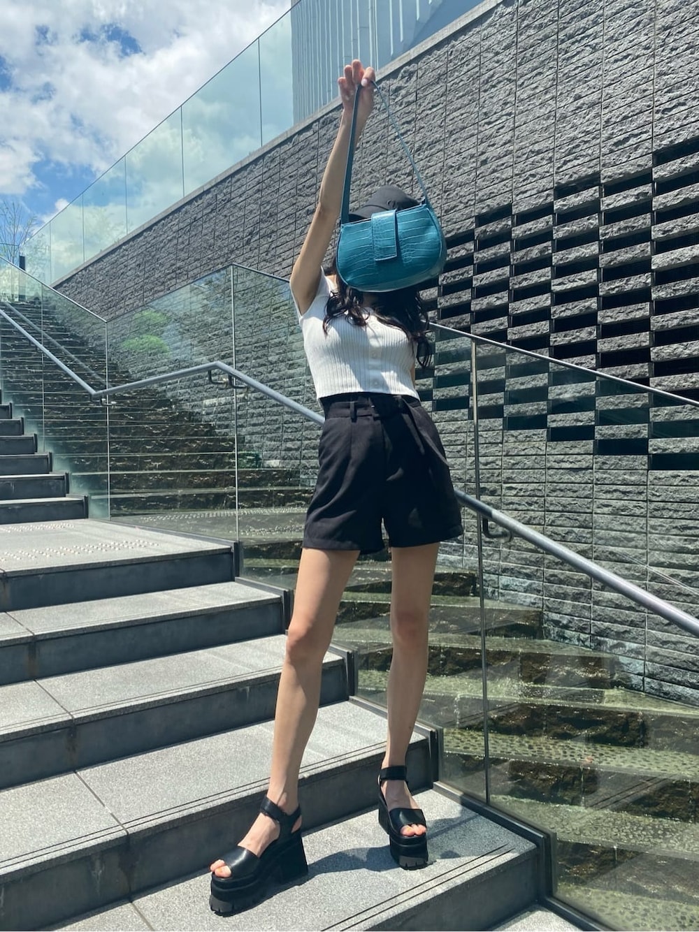 ブルー系のハンドバッグ、ブラック系のその他パンツ、ブラック系のサンダルを着用したレディースの夏コーディネートの1枚目の写真