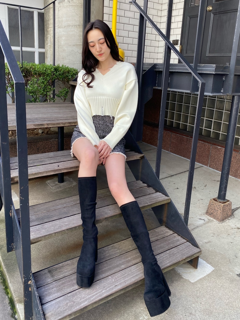 ホワイト系のニット/セーター、ブラック系のブーツを着用したレディースの冬コーディネートの1枚目の写真