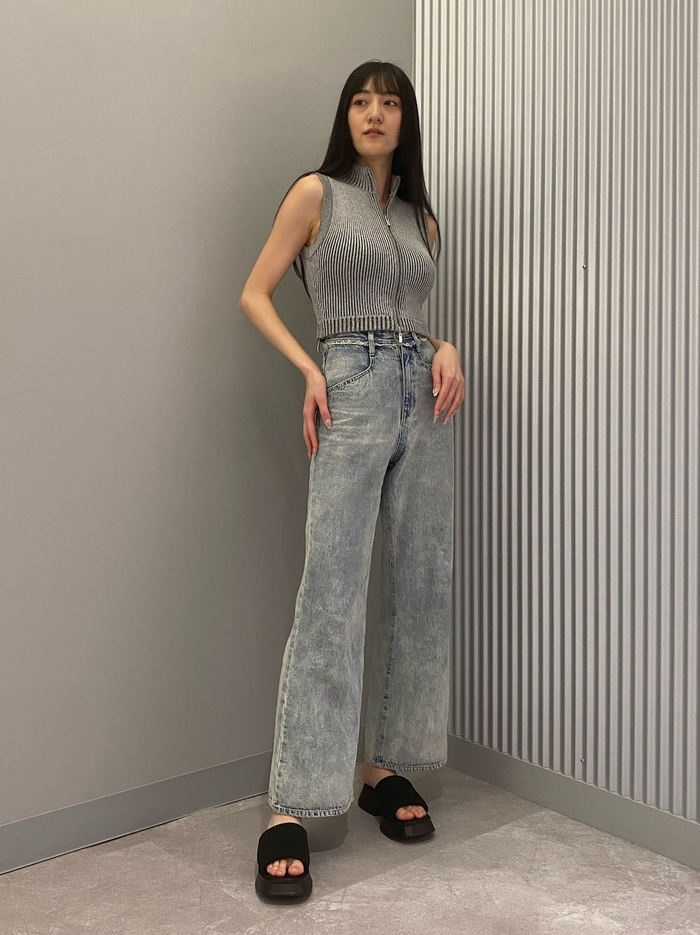 ブルー系のデニムパンツ、グレー系のニット/セーター、ブラック系のサンダルを着用したレディースの春コーディネートの1枚目の写真