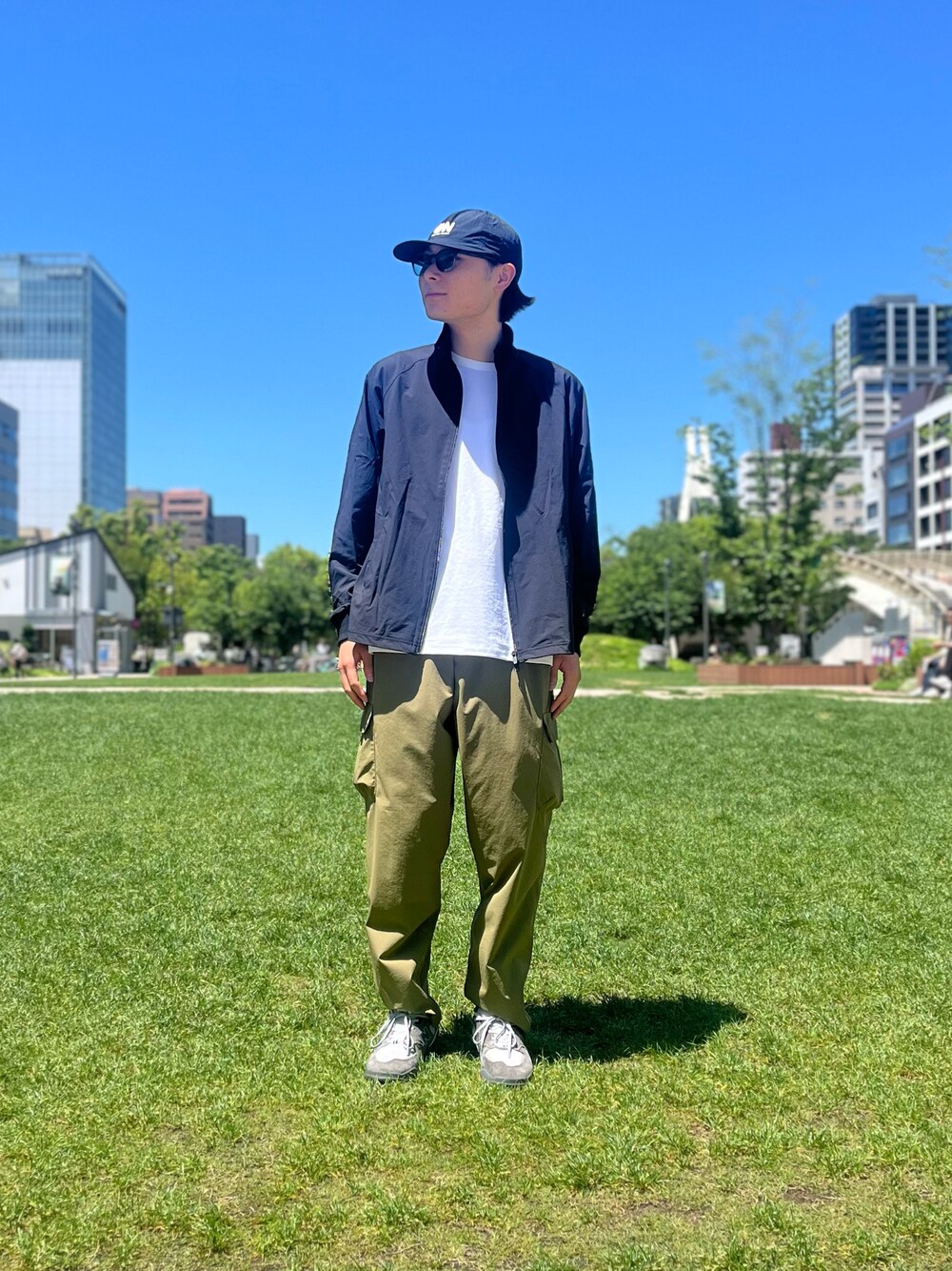 グリーン系のカーゴパンツ、ブラック系のブルゾン、ホワイト系のTシャツ/カットソーを着用したメンズの夏コーディネートの1枚目の写真