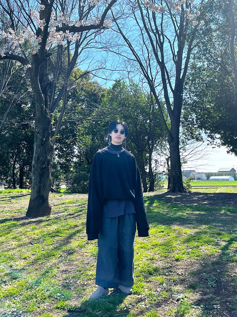 グレー系のカーゴパンツ、ベージュ系のスリッポン、ブラック系のスウェットを着用したメンズの春コーディネートの1枚目の写真